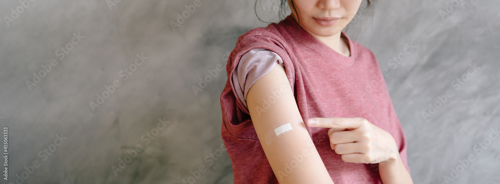 Young Asian woman showing arm after vaccine injection on loft concrete ...