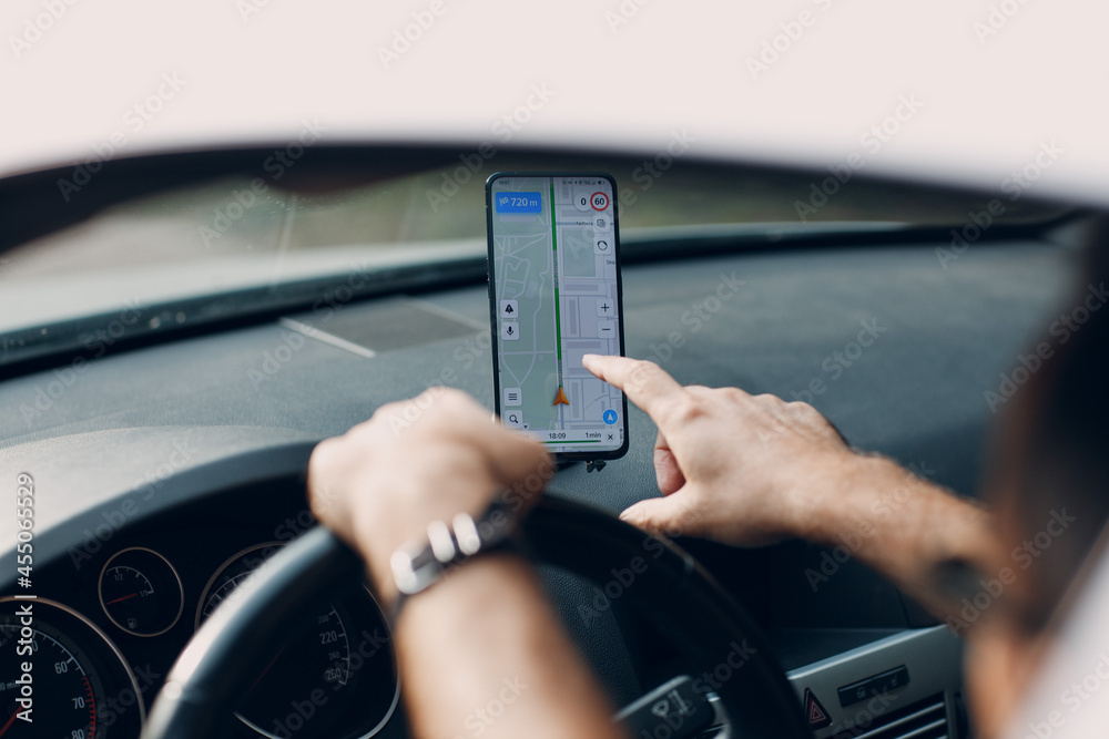 Navigator in car vehicle transportation commuter. Driver man using mobile phone navigator app while driving car.