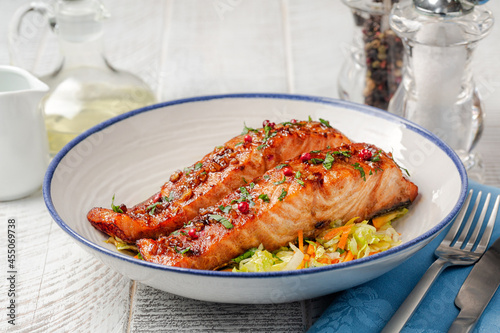 Honey garlic glazed salmon with vegetables in a white plate, white table. Healthy food concept.