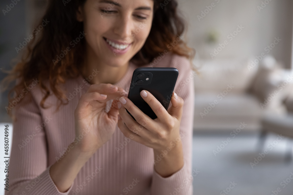 Focus on smartphone in female hands, smiling millennial latin woman using cellphone software applications, typing message or responding email, playing game or shopping online in internet store. Focus on smartphone in female hands, smiling millennial latin woman using cellphone software applications, typing message or responding email, playing game or shopping online in internet store.