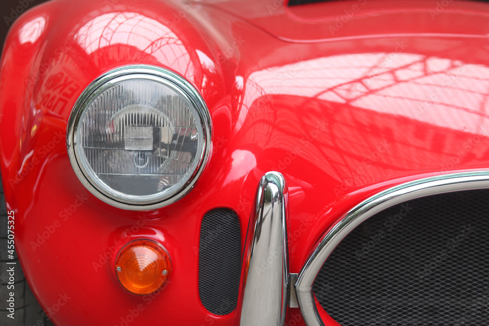 Front of old red car close up with round car headlights