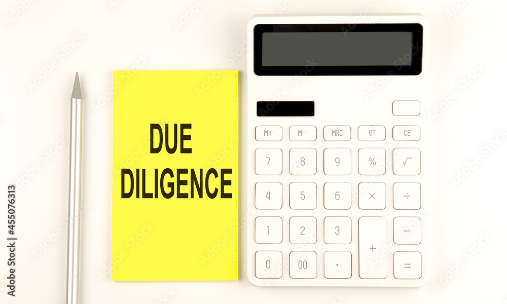 text DUE DILIGENCE on yellow sticker, next to pen and calculator text DUE DILIGENCE on yellow sticker, next to pen and calculator