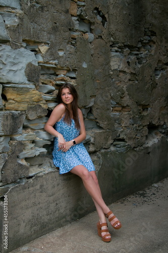 a pretty young woman in a blue dress posing in an alley way.