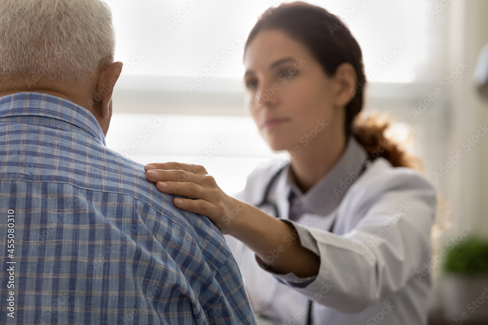 Serious GP doctor giving support to elderly 80s patient after telling bad news, holding, touching shoulder. Older man getting bad diagnosis, hard mental disease, late cancer. Elderly medic care Serious GP doctor giving support to elderly 80s patient after telling bad news, holding, touching shoulder. Older man getting bad diagnosis, hard mental disease, late cancer. Elderly medic care