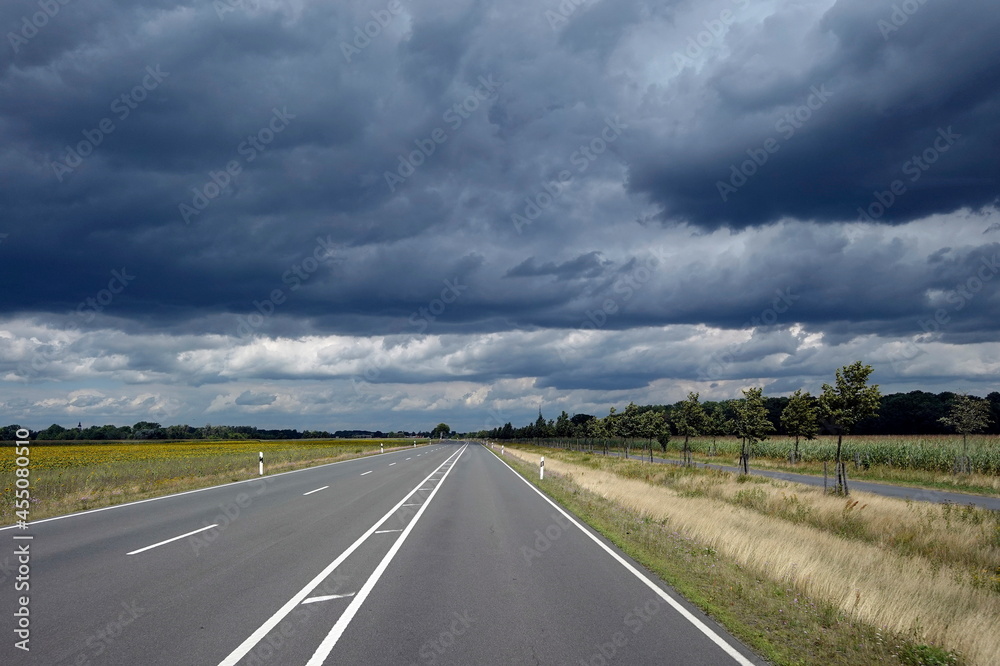 Landstraße, dreispurig, dunkle Wolken am Himmel