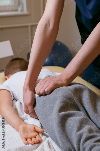Doctor osteopath masseur treats the spine after injury, manual therapy for a child