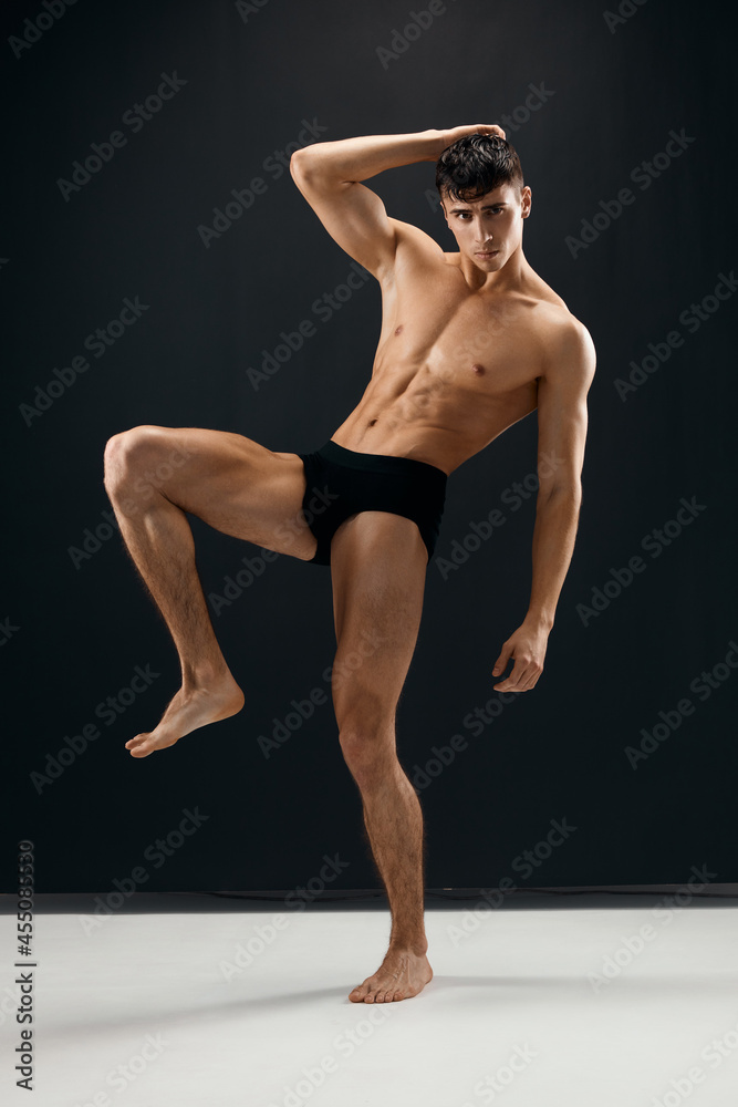 man with a pumped-up muscular body in black shorts dark background man with a pumped-up muscular body in black shorts dark background