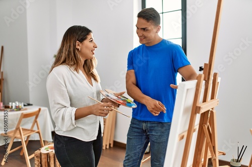 Student and teacher smiling happy painting at art school.