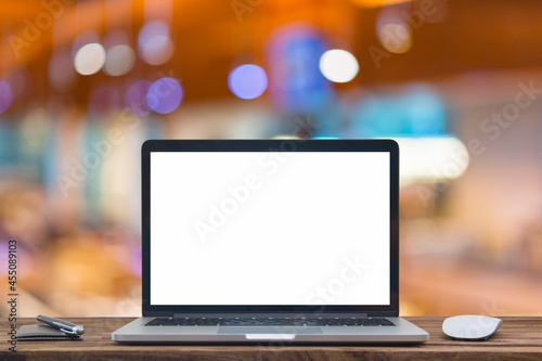 Desk Laptop with blank screen on table of coffee shop blur background