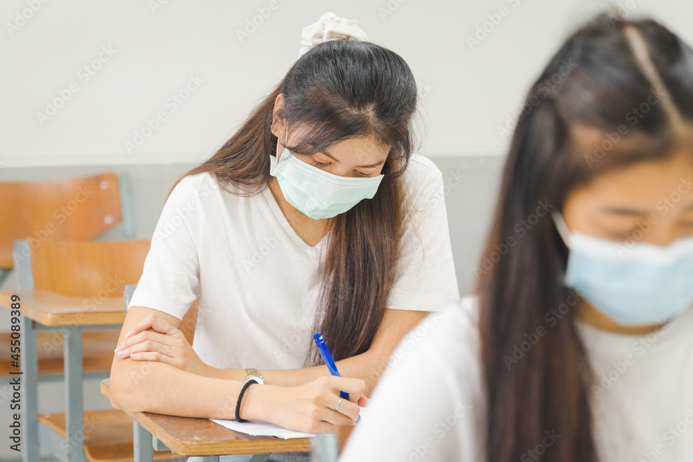 Asian college students back to school wear protective facemask and keep social distance studying in the classroom