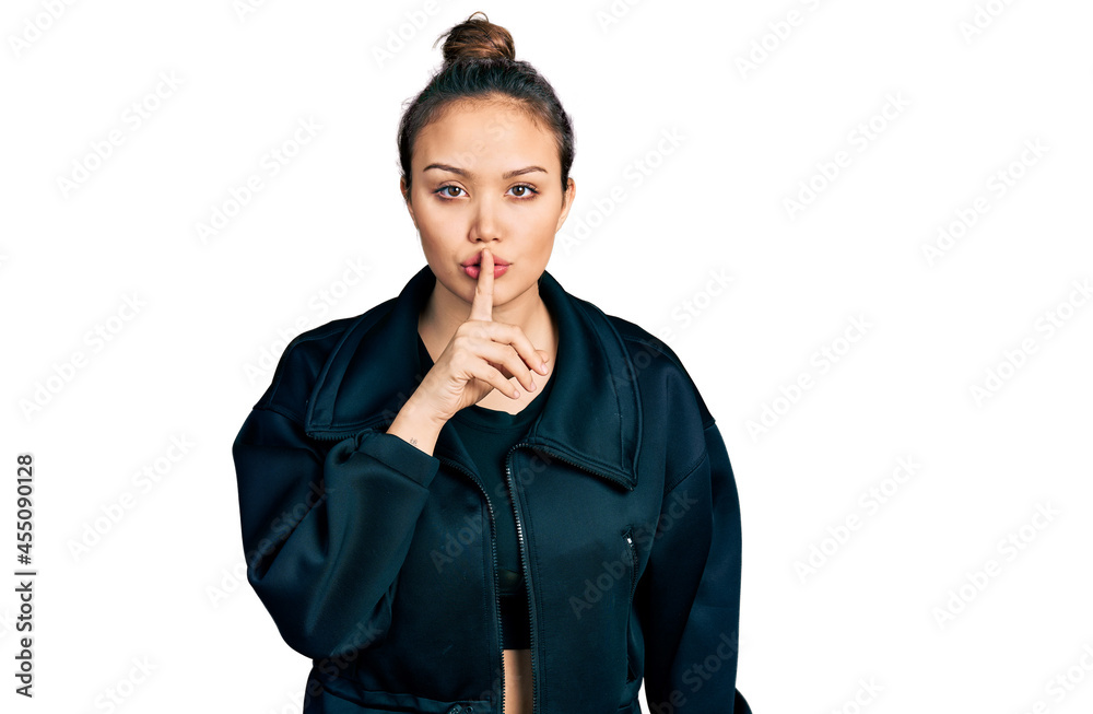 Young hispanic girl wearing sportswear asking to be quiet with finger on lips. silence and secret concept. Young hispanic girl wearing sportswear asking to be quiet with finger on lips. silence and secret concept.