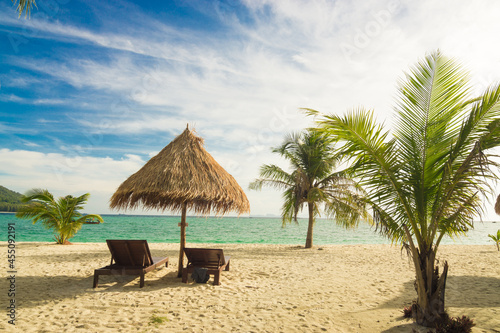 Wooden beach bench on white sand beach with coconut palm tree summer vacation