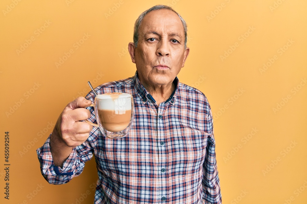 Handsome senior man with grey hair drinking a cup coffee looking at the camera blowing a kiss on air being lovely and sexy. love expression. Handsome senior man with grey hair drinking a cup coffee looking at the camera blowing a kiss on air being lovely and sexy. love expression.