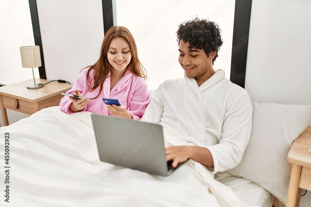 Young couple smiling happy using laptop, smartphone and credit card at bedroom. Young couple smiling happy using laptop, smartphone and credit card at bedroom.