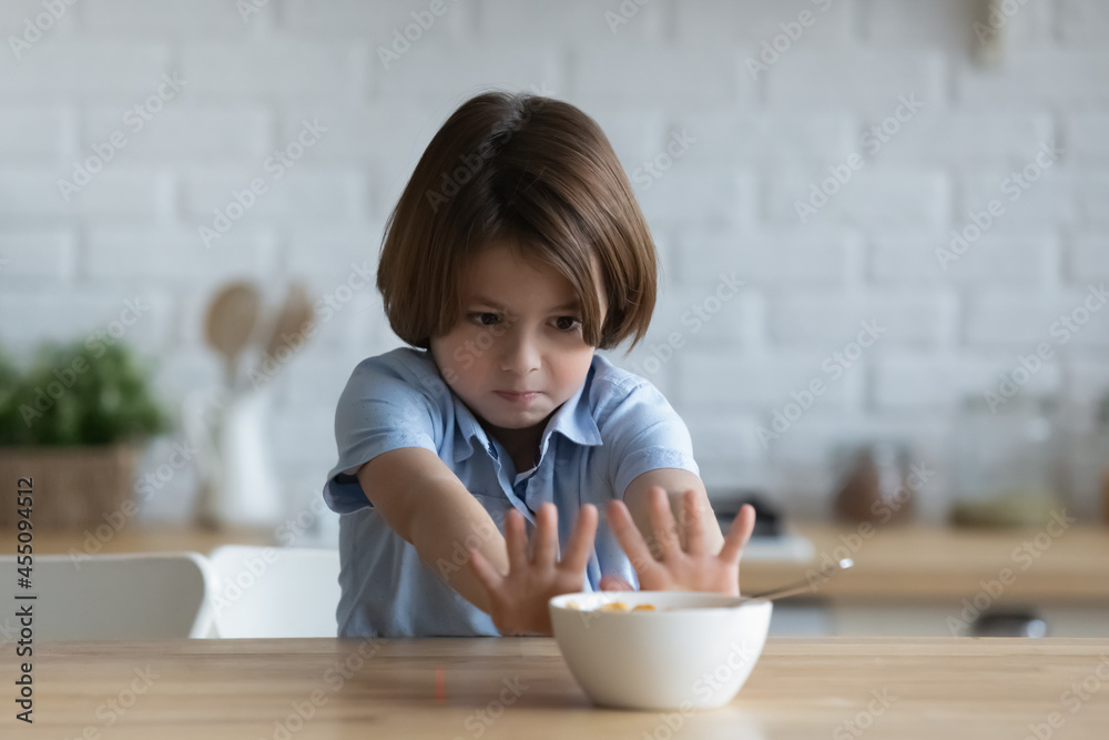 Stubborn little kid boy rejecting eating dry breakfast corn flakes with milk, sitting in kitchen without appetite. Upset small male child does not want eating tasteless food, loss of appetite. Stubborn little kid boy rejecting eating dry breakfast corn flakes with milk, sitting in kitchen without appetite. Upset small male child does not want eating tasteless food, loss of appetite.