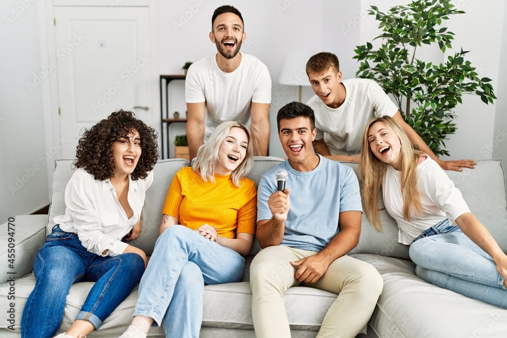 Group of young friends having party singing song using microphone at home. Group of young friends having party singing song using microphone at home.