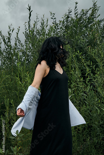Dreamy portrait of woman in summer park outdoors. Close up, brunette young lady in black dress and blouse. Summer fashion and beauty.
