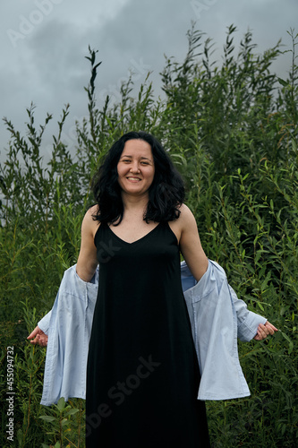 Dreamy portrait of woman in summer park outdoors. Close up, brunette young lady in black dress and blouse. Summer fashion and beauty.