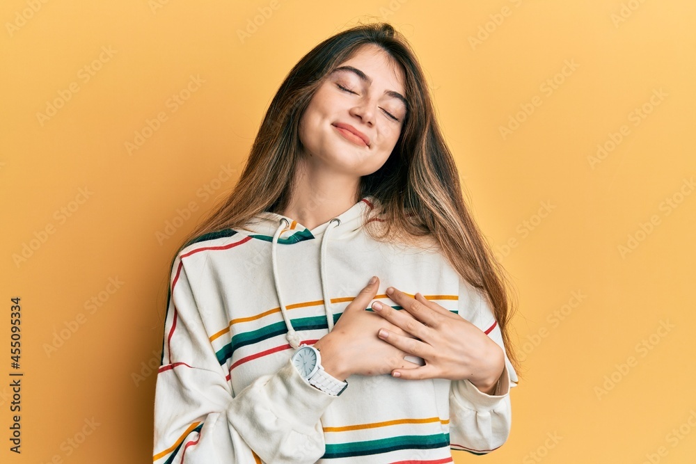 Young caucasian woman wearing casual clothes smiling with hands on chest with closed eyes and grateful gesture on face. health concept. Young caucasian woman wearing casual clothes smiling with hands on chest with closed eyes and grateful gesture on face. health concept.