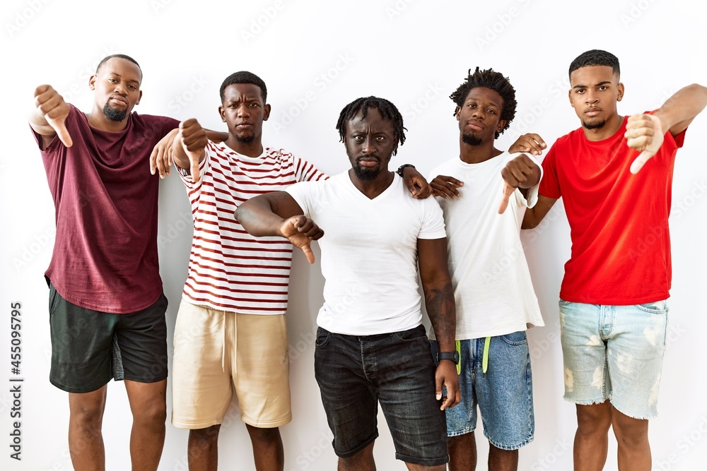 Obraz premium Young african group of friends standing together over isolated background looking unhappy and angry showing rejection and negative with thumbs down gesture. bad expression.