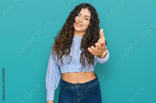 Young hispanic girl wearing casual clothes smiling cheerful offering palm hand giving assistance and acceptance. photo