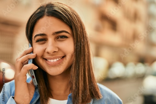 Young latin girl smiling happy talking on the smartphone at the city.