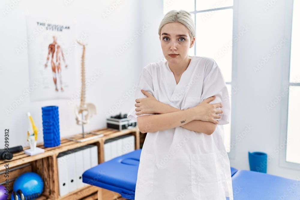 Young caucasian woman working at pain recovery clinic shaking and freezing for winter cold with sad and shock expression on face Young caucasian woman working at pain recovery clinic shaking and freezing for winter cold with sad and shock expression on face