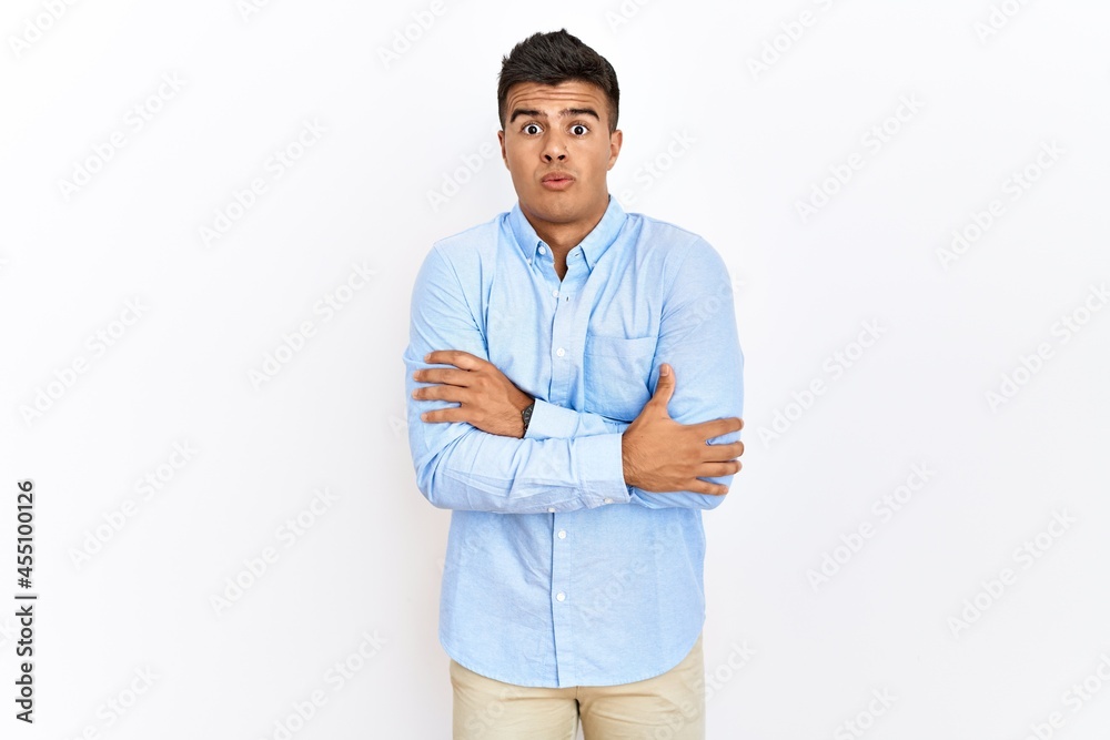Young hispanic man wearing business shirt standing over isolated background shaking and freezing for winter cold with sad and shock expression on face Young hispanic man wearing business shirt standing over isolated background shaking and freezing for winter cold with sad and shock expression on face