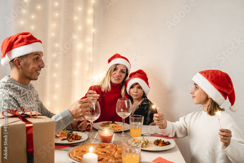Happy family celebrating Christmas with sparklers during vegan dinner party - Focus girl face