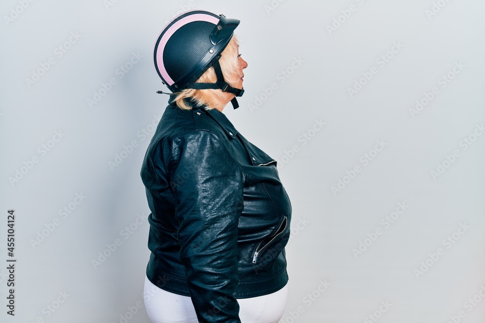 Middle age blonde woman holding motorcycle helmet looking to side, relax profile pose with natural face with confident smile. Middle age blonde woman holding motorcycle helmet looking to side, relax profile pose with natural face with confident smile.
