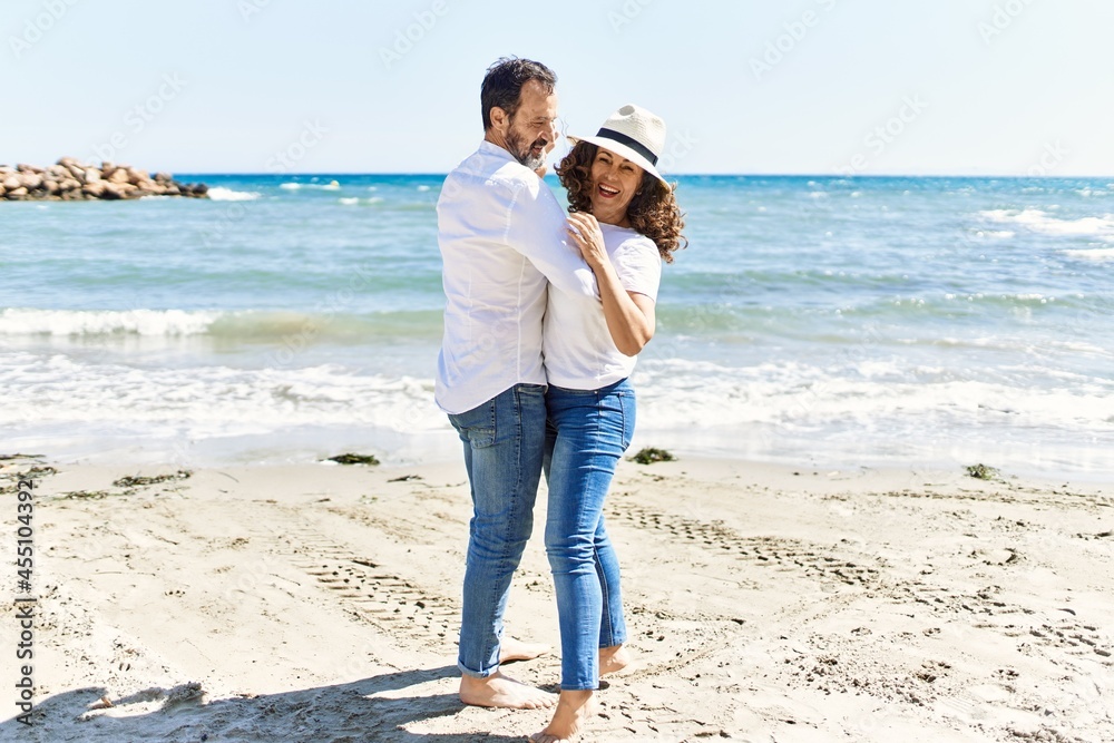 Middle age hispanic couple smiling happy dancing at the beach. Middle age hispanic couple smiling happy dancing at the beach.