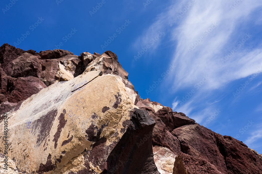 Huge red and yellow rock cliff on red sand beach Santorini. Alien landscape.