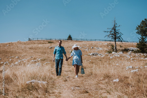 Loving couple holding hands while going down the mountain on a sunny day. Man and woman holding hands and happily going down the mountain while enjoying their moment.