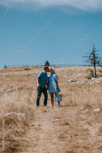 Loving couple holding hands while going down the mountain on a sunny day. Man and woman holding hands and happily going down the mountain while enjoying their moment. © Dinno