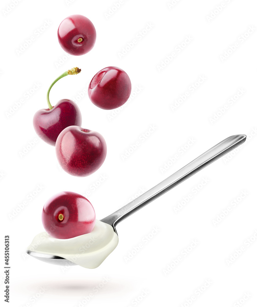 Isolated yogurt with fruits. Spoon with natural yogurt and cherries flying over it isolated on white background Isolated yogurt with fruits. Spoon with natural yogurt and cherries flying over it isolated on white background