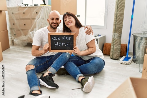 Young hispanic couple smiling happy holding our new home blackboard at new home.