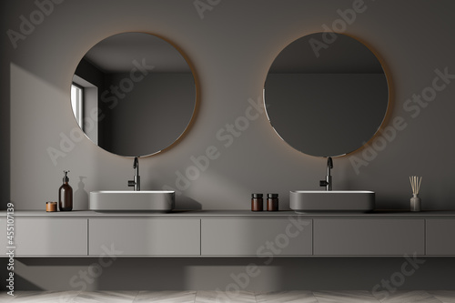 View of a grey bathroom wall hung double vanity with round mirrors