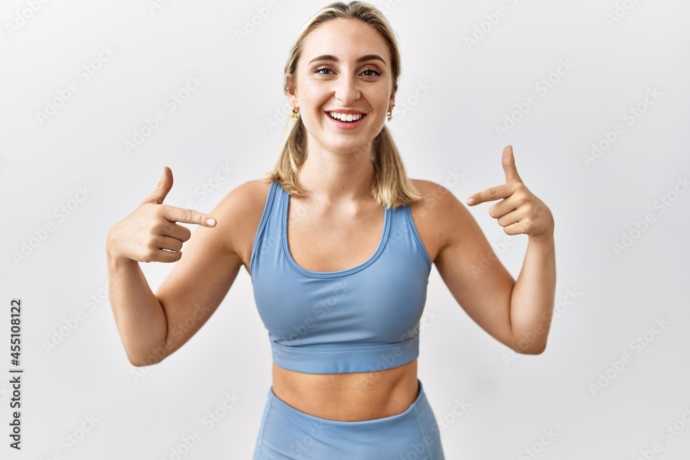 Young blonde woman wearing sportswear over isolated background looking confident with smile on face, pointing oneself with fingers proud and happy. Young blonde woman wearing sportswear over isolated background looking confident with smile on face, pointing oneself with fingers proud and happy.