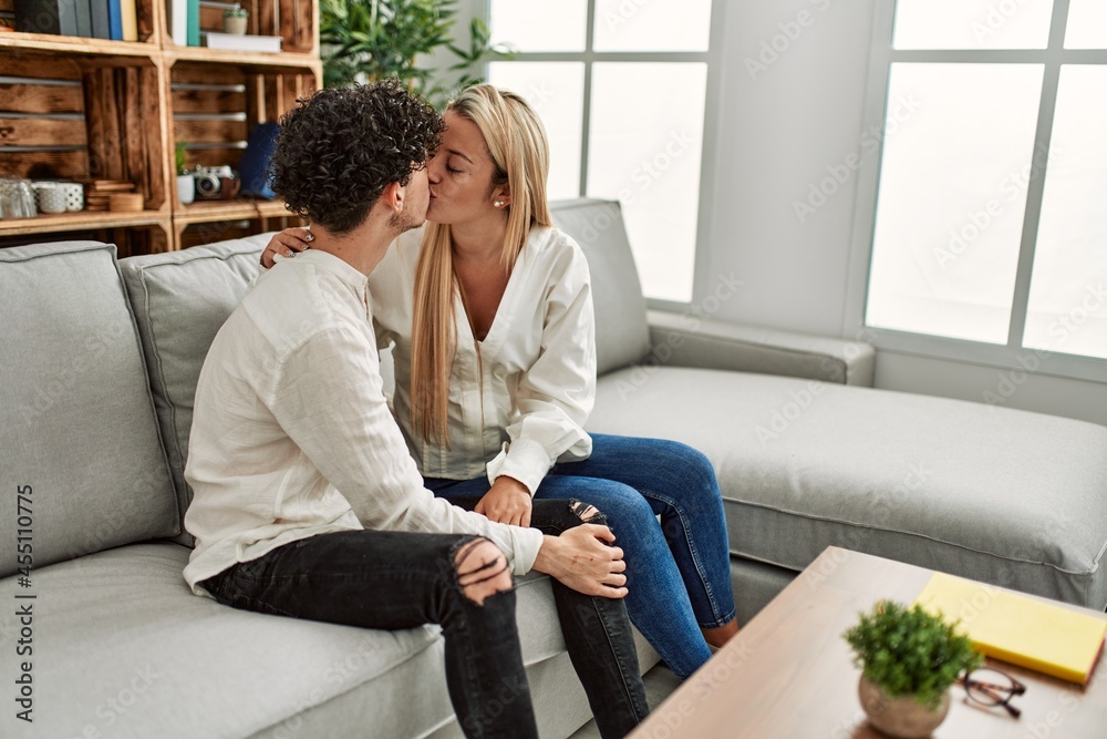 Young couple sitting on the sofa hugging and kissing at home. Young couple sitting on the sofa hugging and kissing at home.