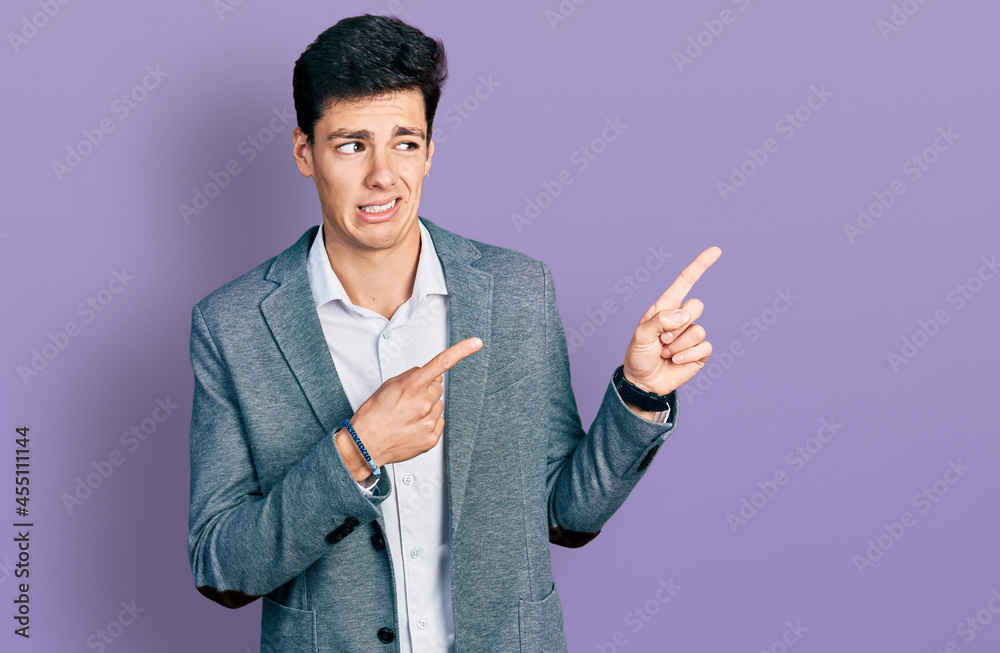 Young hispanic man wearing business clothes pointing aside worried and nervous with both hands, concerned and surprised expression Young hispanic man wearing business clothes pointing aside worried and nervous with both hands, concerned and surprised expression