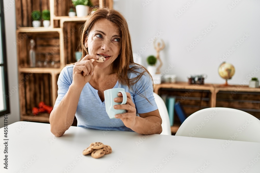 Middle age caucasian woman having breakfast sitting on the table at home.