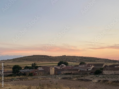 Tableau sur toile Paraje de pueblo, atardecer con casas lejanas en campo