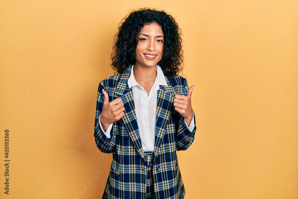 Young latin girl wearing business clothes success sign doing positive gesture with hand, thumbs up smiling and happy. cheerful expression and winner gesture. Young latin girl wearing business clothes success sign doing positive gesture with hand, thumbs up smiling and happy. cheerful expression and winner gesture.