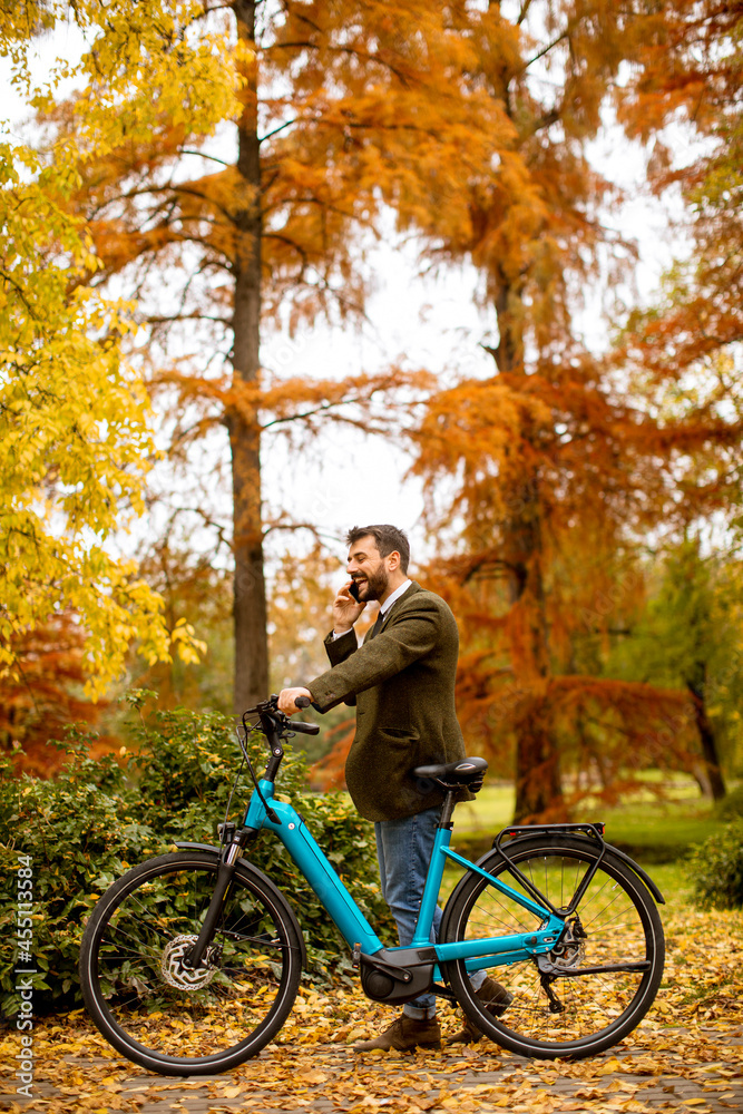 Fototapeta premium Young man with electric bicycle in the autumn park