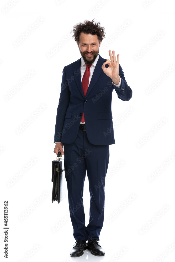 handsome businessman giving an ok sign and holding a briefcase handsome businessman giving an ok sign and holding a briefcase