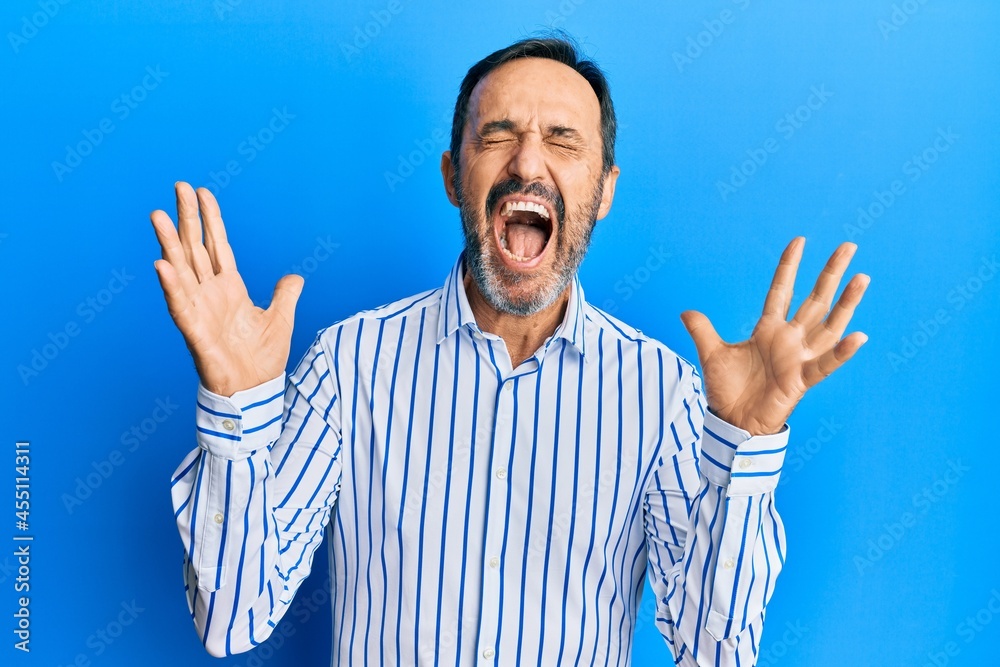 Middle age hispanic man wearing casual clothes celebrating mad and crazy for success with arms raised and closed eyes screaming excited. winner concept Middle age hispanic man wearing casual clothes celebrating mad and crazy for success with arms raised and closed eyes screaming excited. winner concept