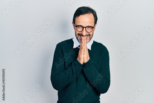 Middle age hispanic man wearing casual clothes and glasses praying with hands together asking for forgiveness smiling confident. © Krakenimages.com