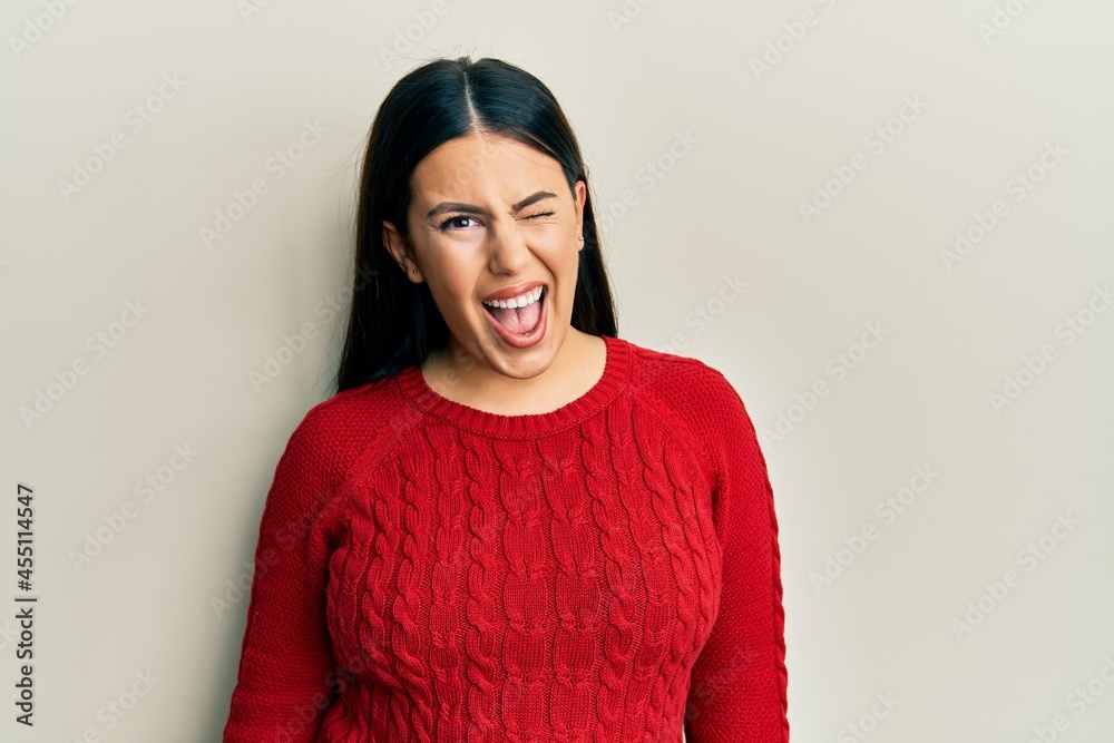 Beautiful brunette woman wearing wool winter sweater winking looking at the camera with sexy expression, cheerful and happy face. Beautiful brunette woman wearing wool winter sweater winking looking at the camera with sexy expression, cheerful and happy face.