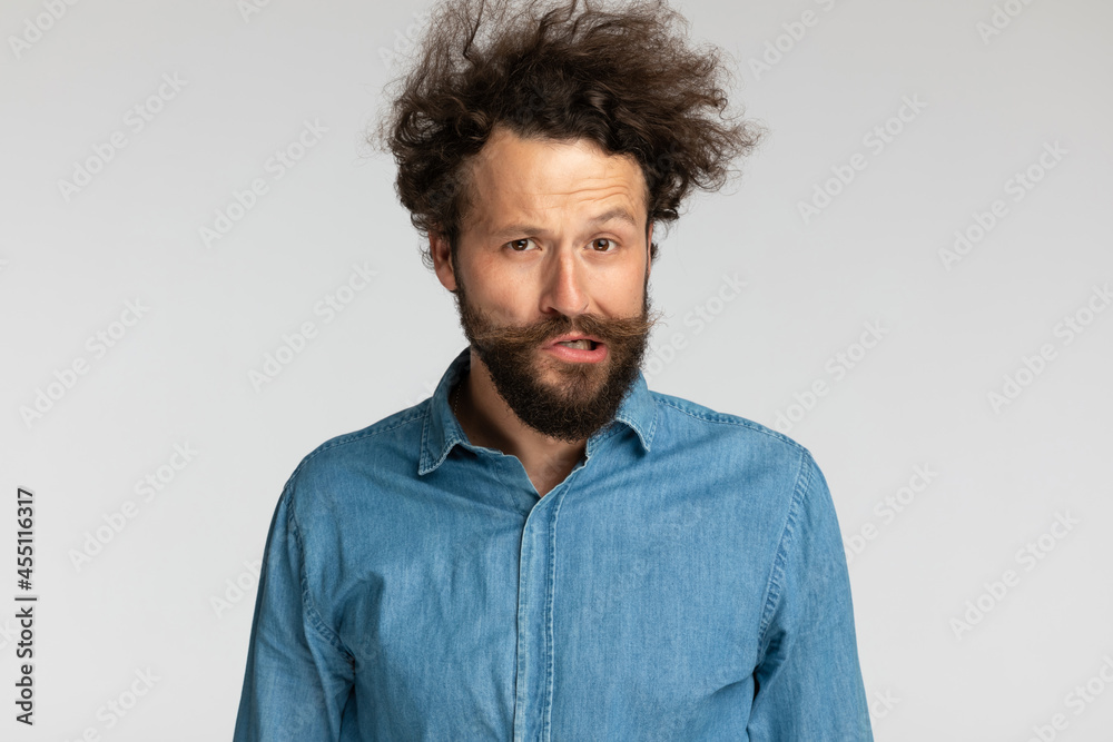 young casual man in denim shirt with curly hair making funny faces young casual man in denim shirt with curly hair making funny faces