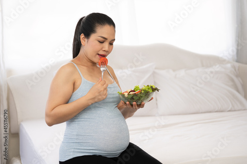 Pregnant woman eating salad healthy food for breakfast in bedroom at home.pregnancy, healthy food and people concept.